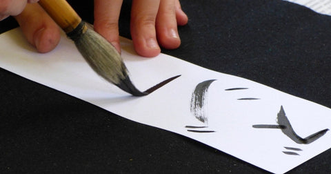 Hand writing Japanese characters with a calligraphy brush and black ink
